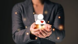 Person holding a glowing house icon with a heart symbol.