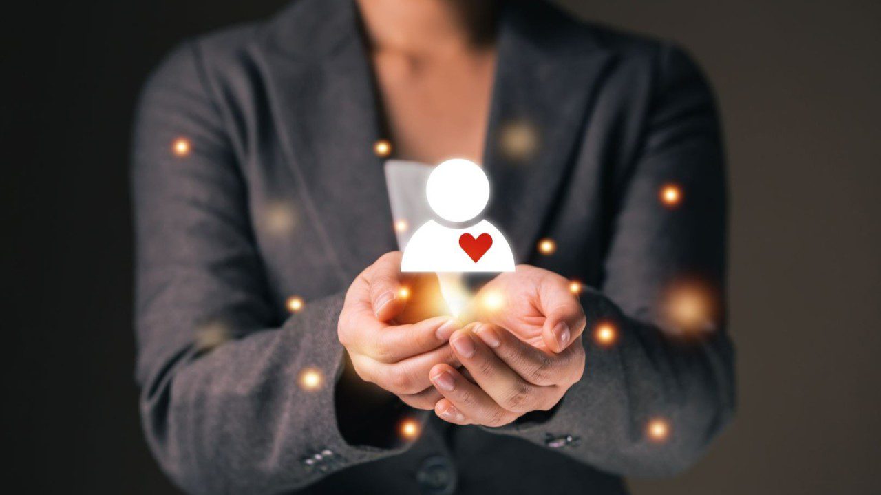 Person holding a glowing house icon with a heart symbol.