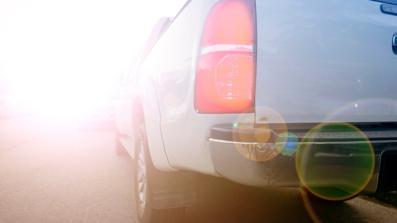 Rear side of a white vehicle with sunlight flare.