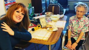 Two women enjoying tea at a cozy kitchen table with snacks.