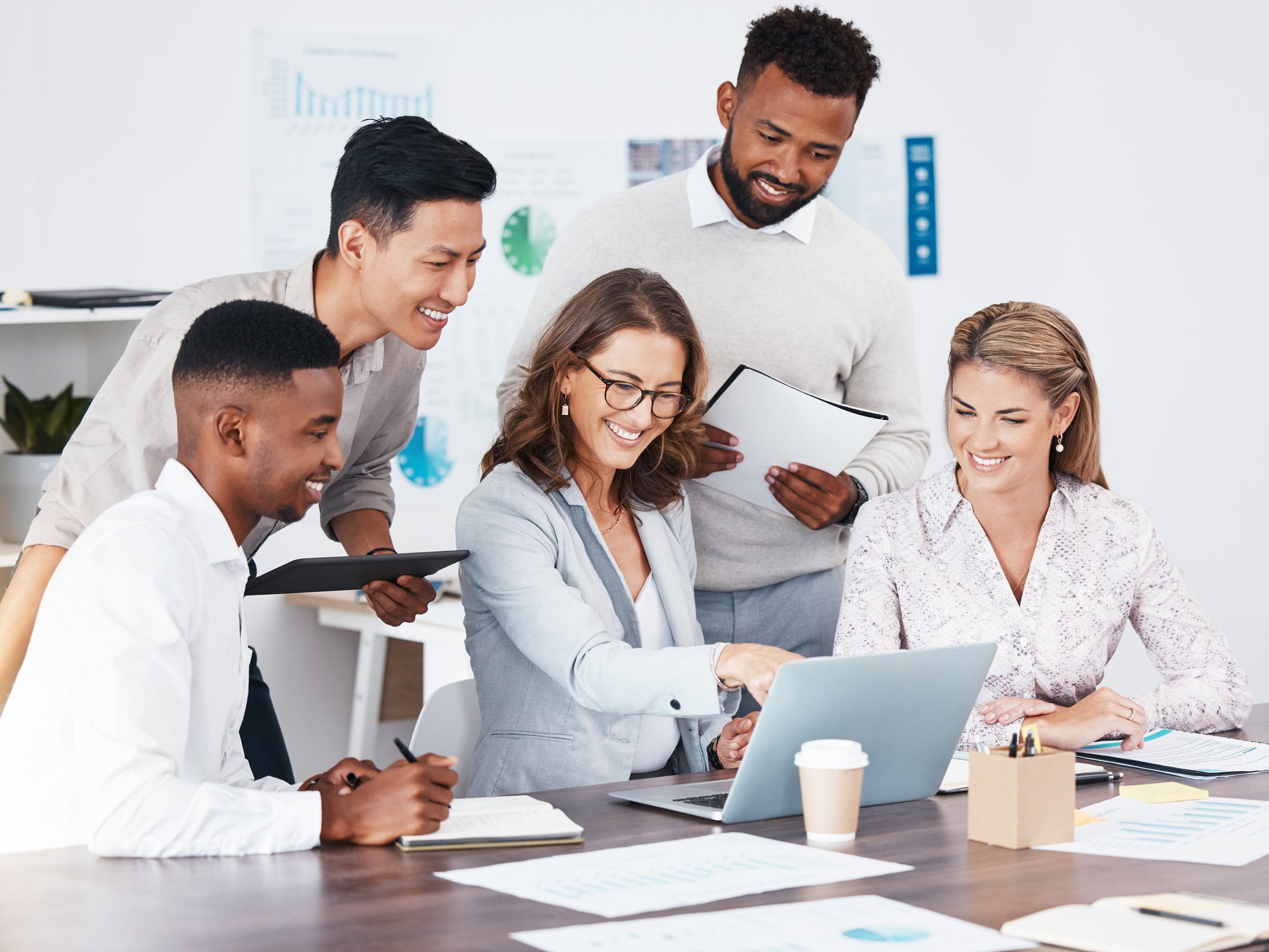 Group collaborating around a laptop in office.